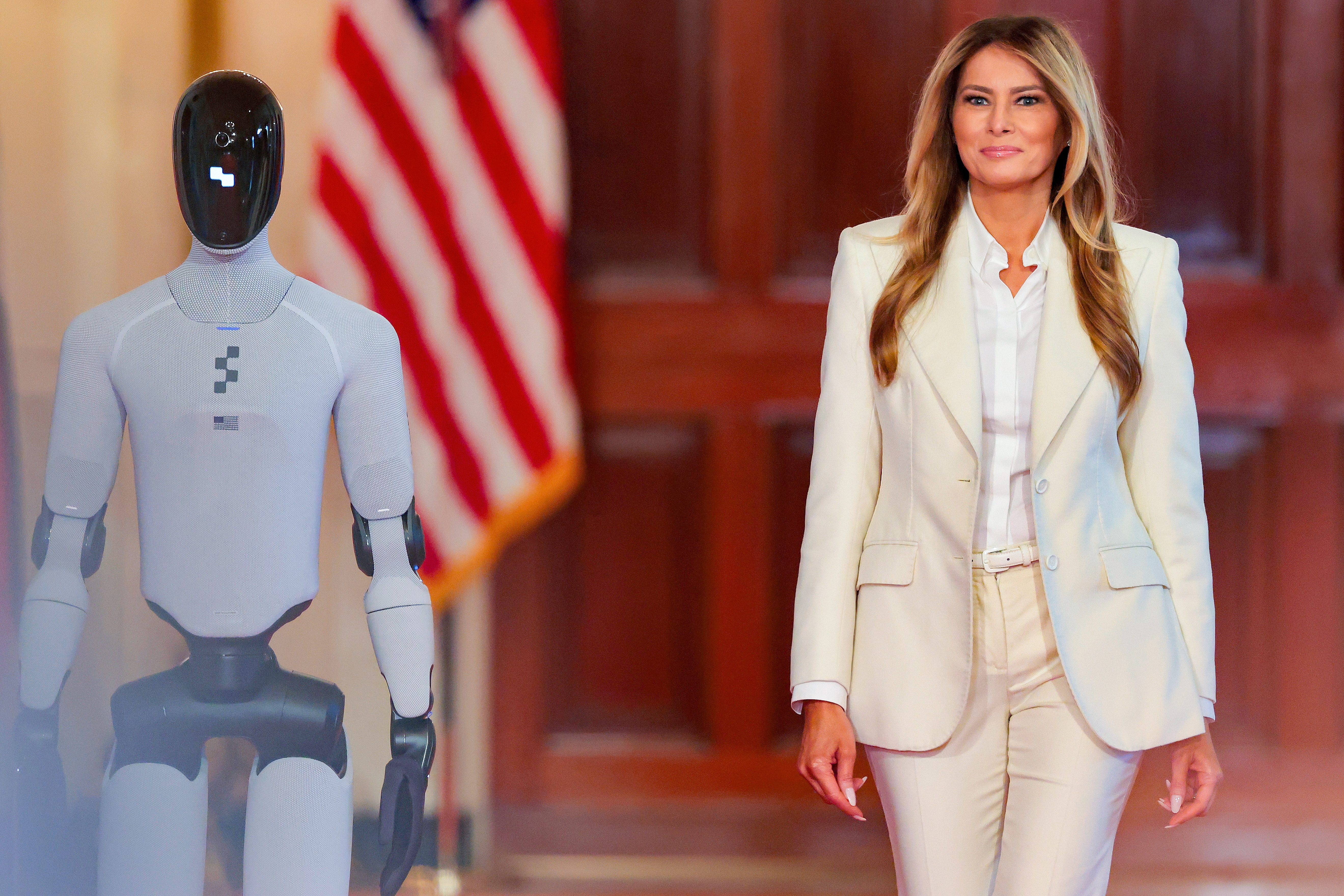 Melania Trump walking beside a humanoid robot in the White House East Room