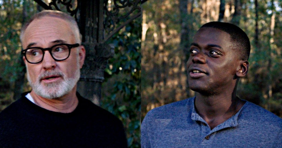 Middle-aged bald man with white beard and black glasses looking to the side, standing outdoors among dark green foliage.