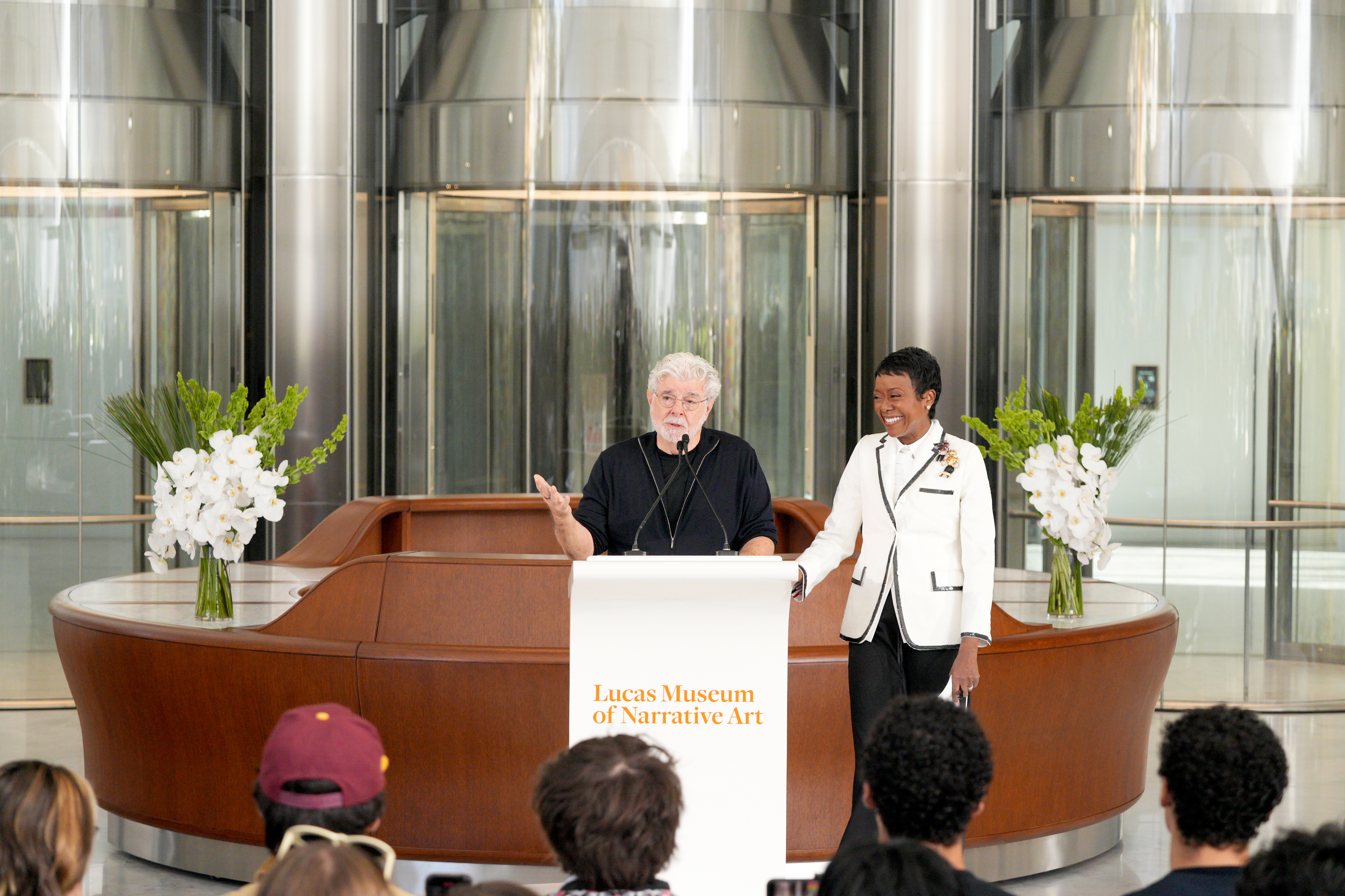 George Lucas and Mellody Hobson speaking onstage at the Lucas Museum of Narrative Art opening day in Los Angeles