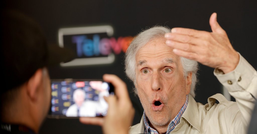 Henry Winkler gesturing expressively while speaking into a microphone at the TV Academy's Televerse Festival in Los Angeles.