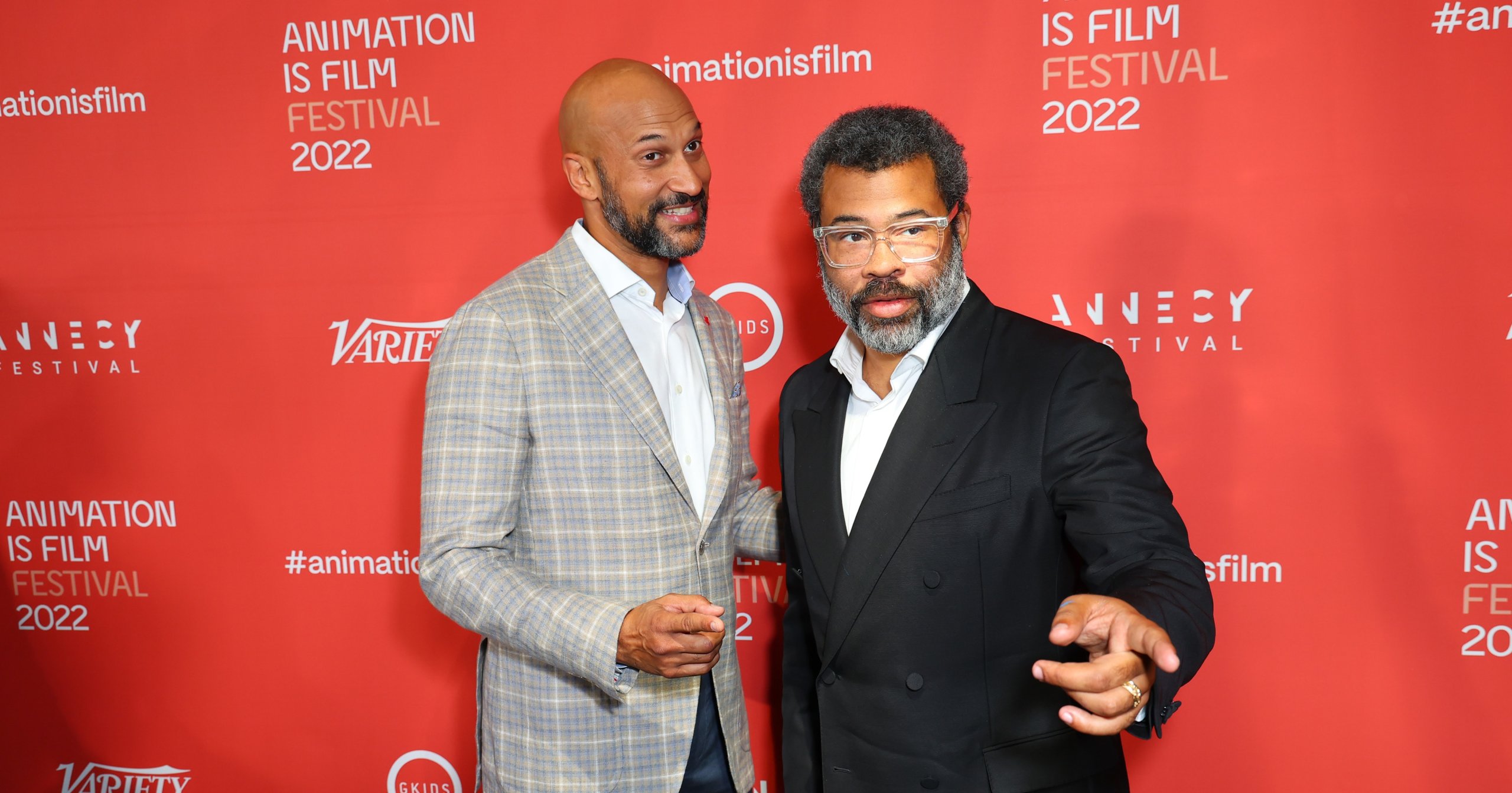 Keegan-Michael Key in a plaid blazer and Jordan Peele in a black suit standing together at the Animation is Film Festival 2022 red carpet event.