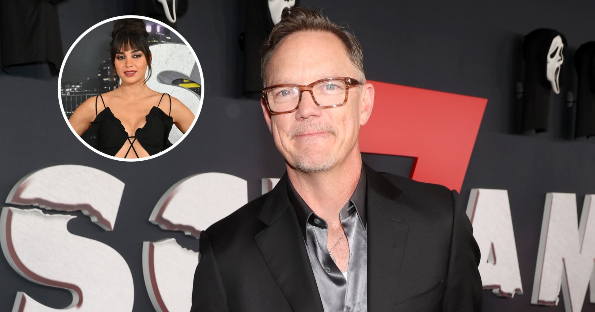 Matthew Lillard in a black suit and silver satin shirt at the Scream 7 premiere, standing in front of a backdrop featuring Ghostface masks.