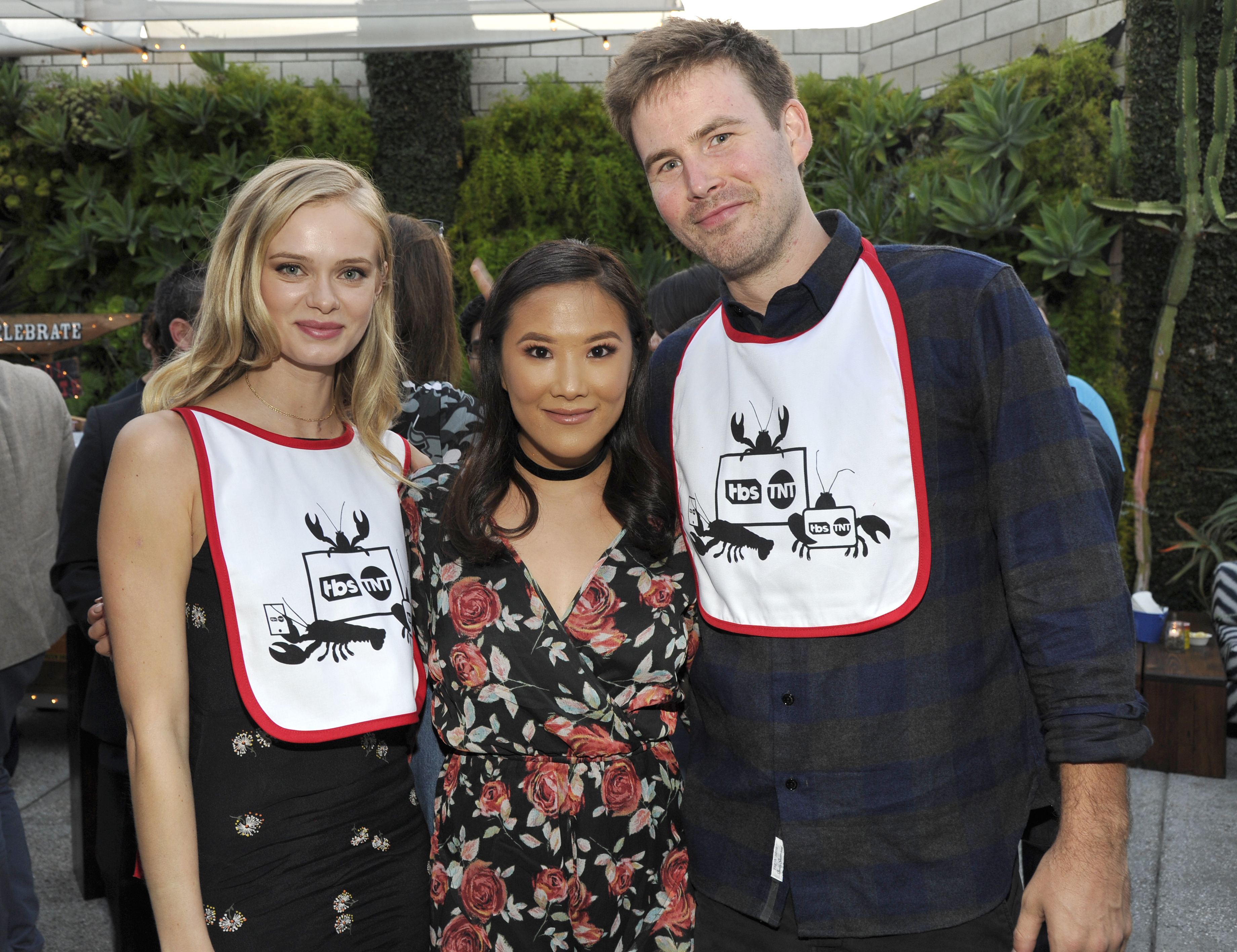 Sara Paxton, Ally Maki, and Zach Cregger wearing TBS/TNT lobster bibs at an outdoor event in Santa Monica.