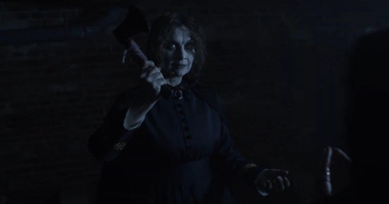 Movie poster for Lizzie Borden: The Hatchet House showing a pale, sinister woman in a dark cape holding a bloody axe in front of a dimly lit window.