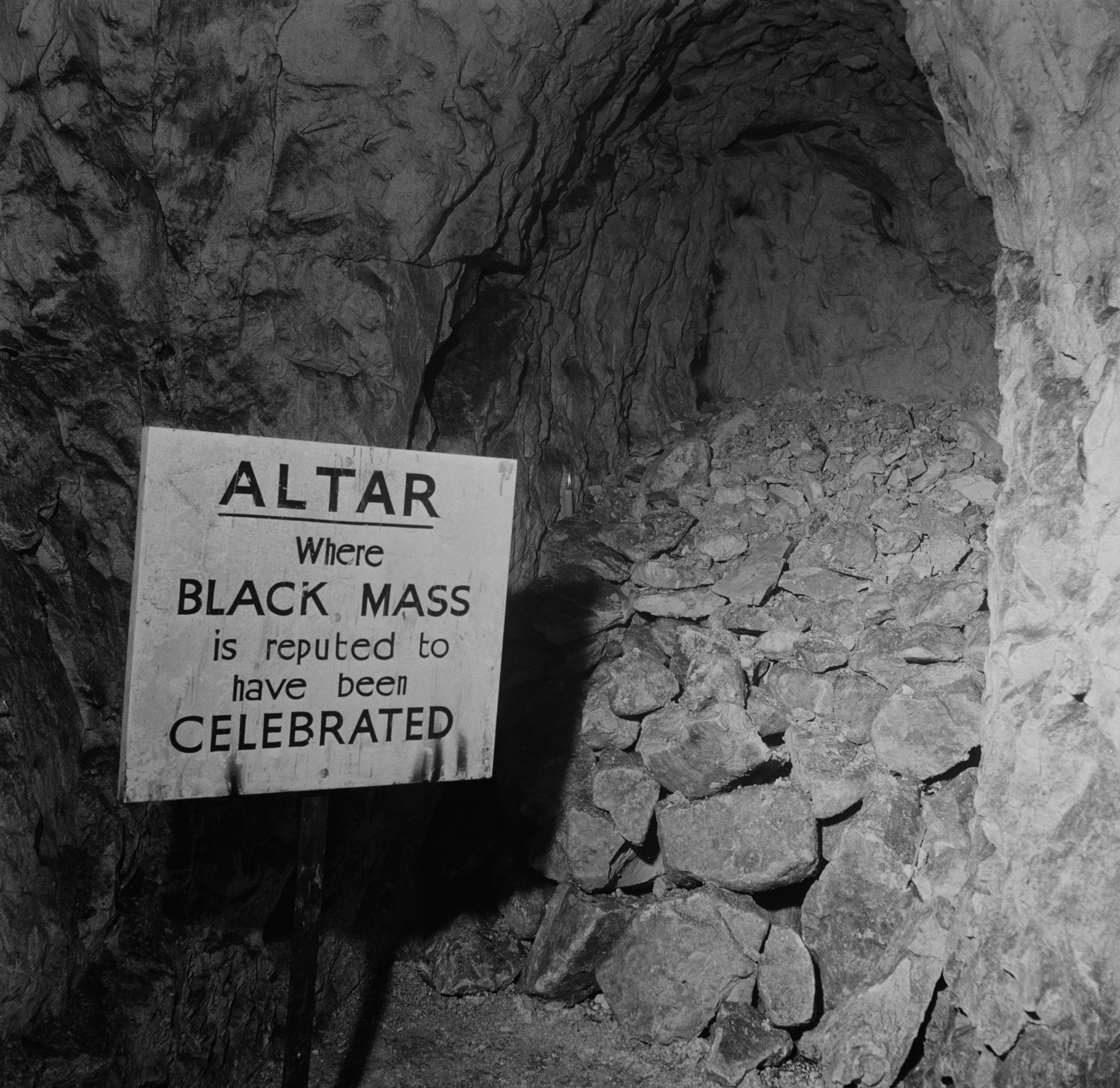 A sign reading 'Altar Where Black Mass is Reputed to Have Been Celebrated' inside the dimly lit Hellfire Caves beneath West Wycombe, Buckinghamshire, 1954.