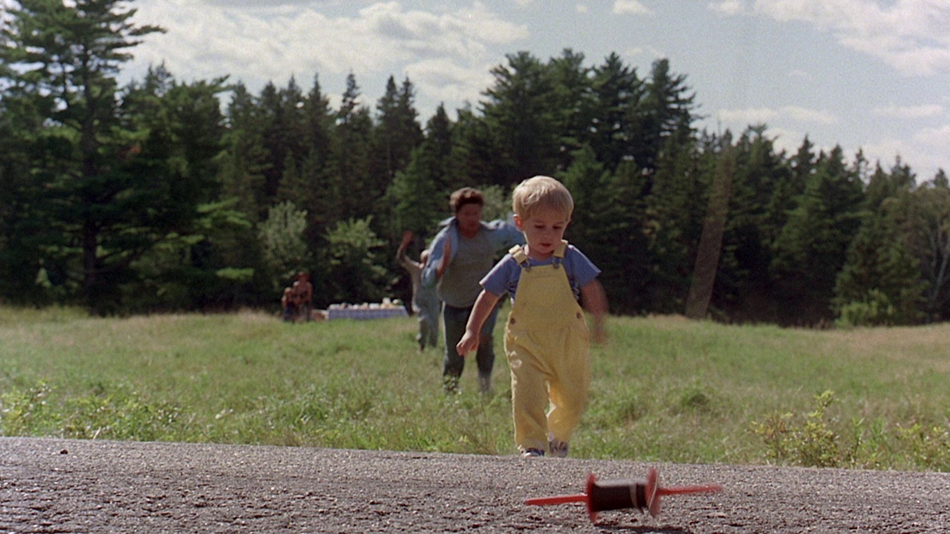 Louis Creed collapsing in grief beside a road in a scene from Pet Sematary (1989)