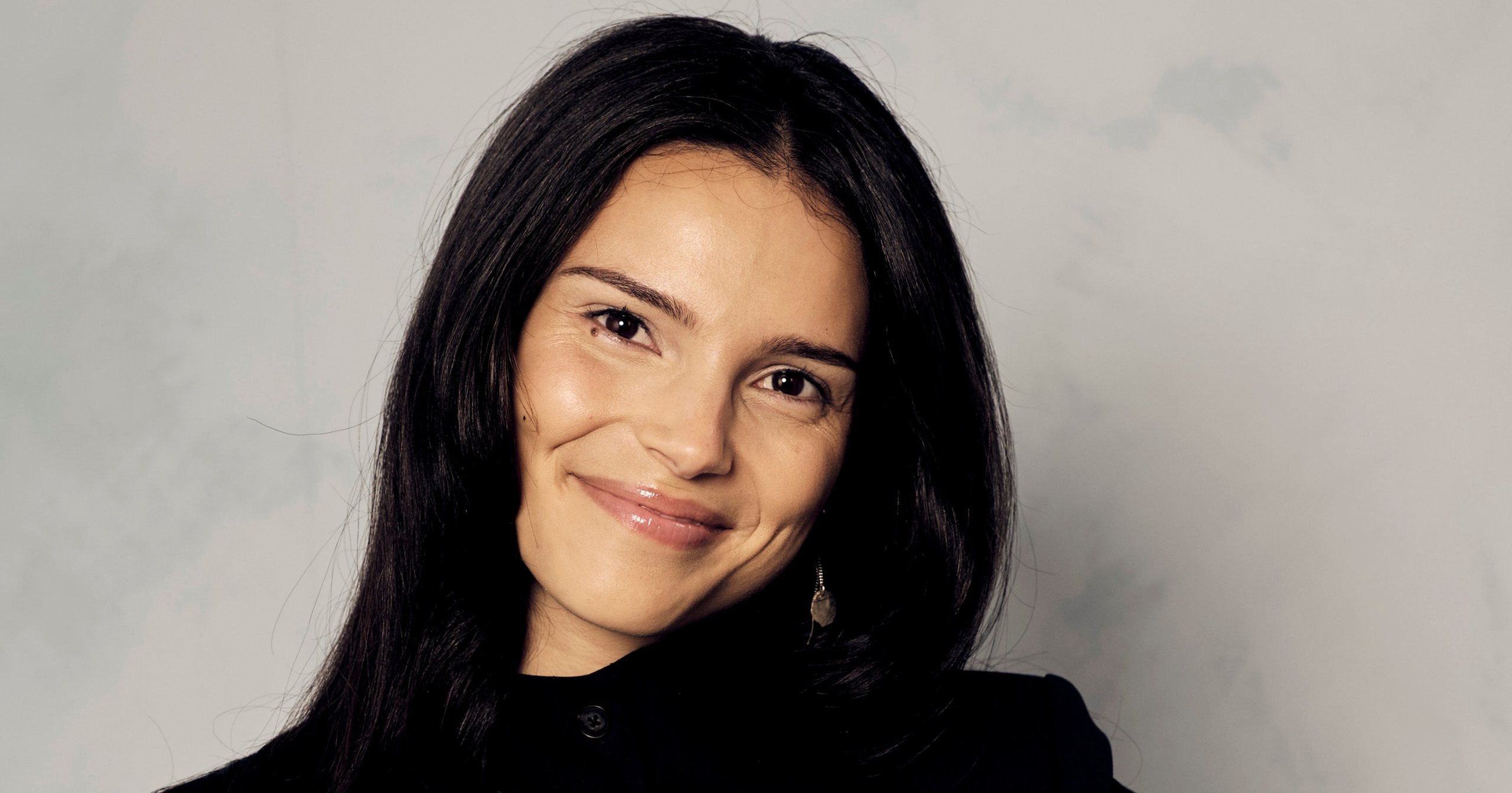 Inde Navarrette smiling and holding an IMDb STARmeter Award trophy at a portrait studio in Toronto.