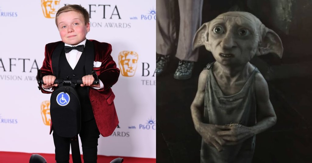 Young boy in a red velvet tuxedo jacket and bow tie standing on a mobility scooter on the red carpet at the BAFTA Television Awards.