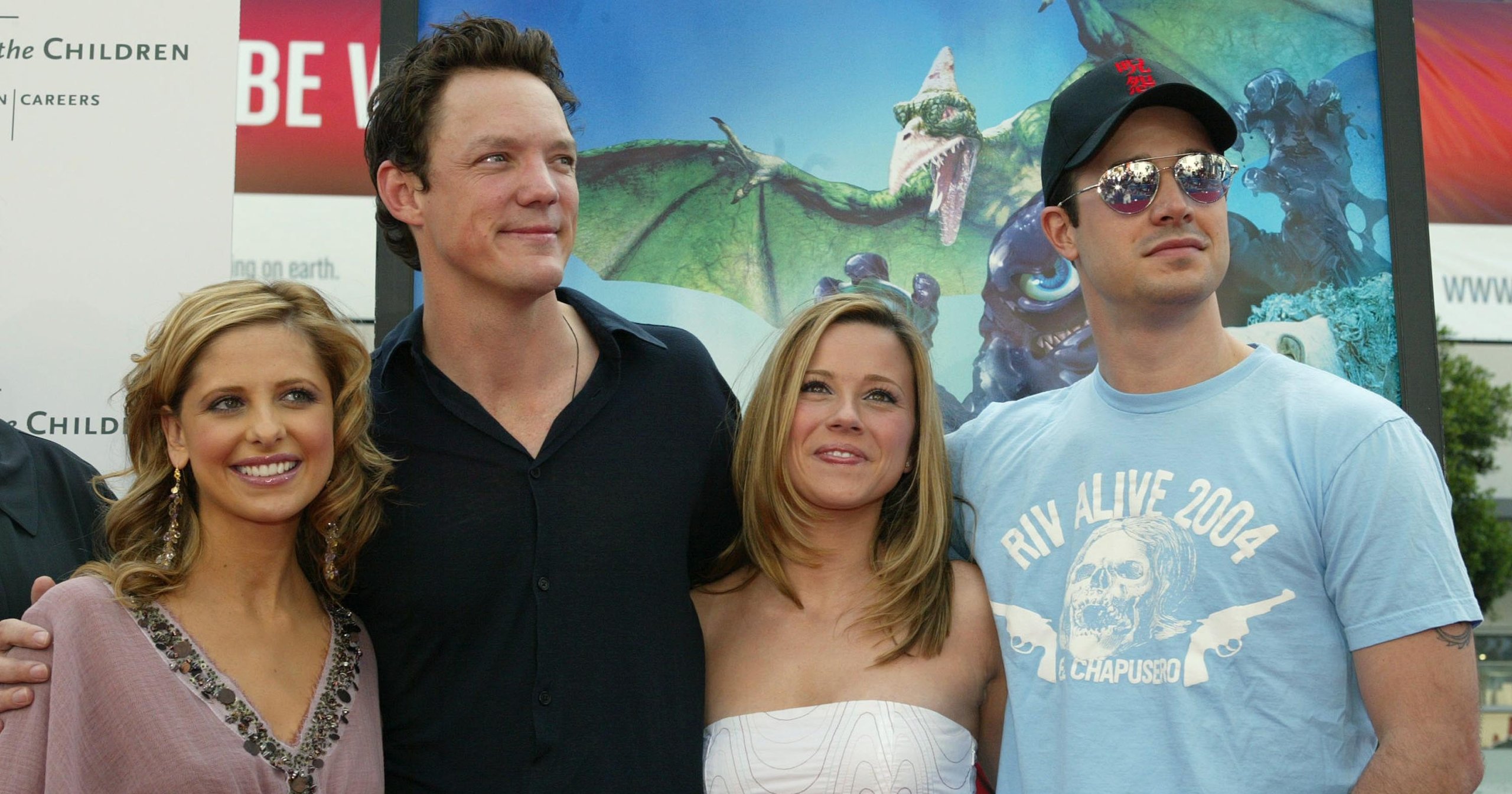 Four people posing in front of a Scooby-Doo 2 movie poster: two women flanked by two men, one wearing a blue cap and sunglasses.