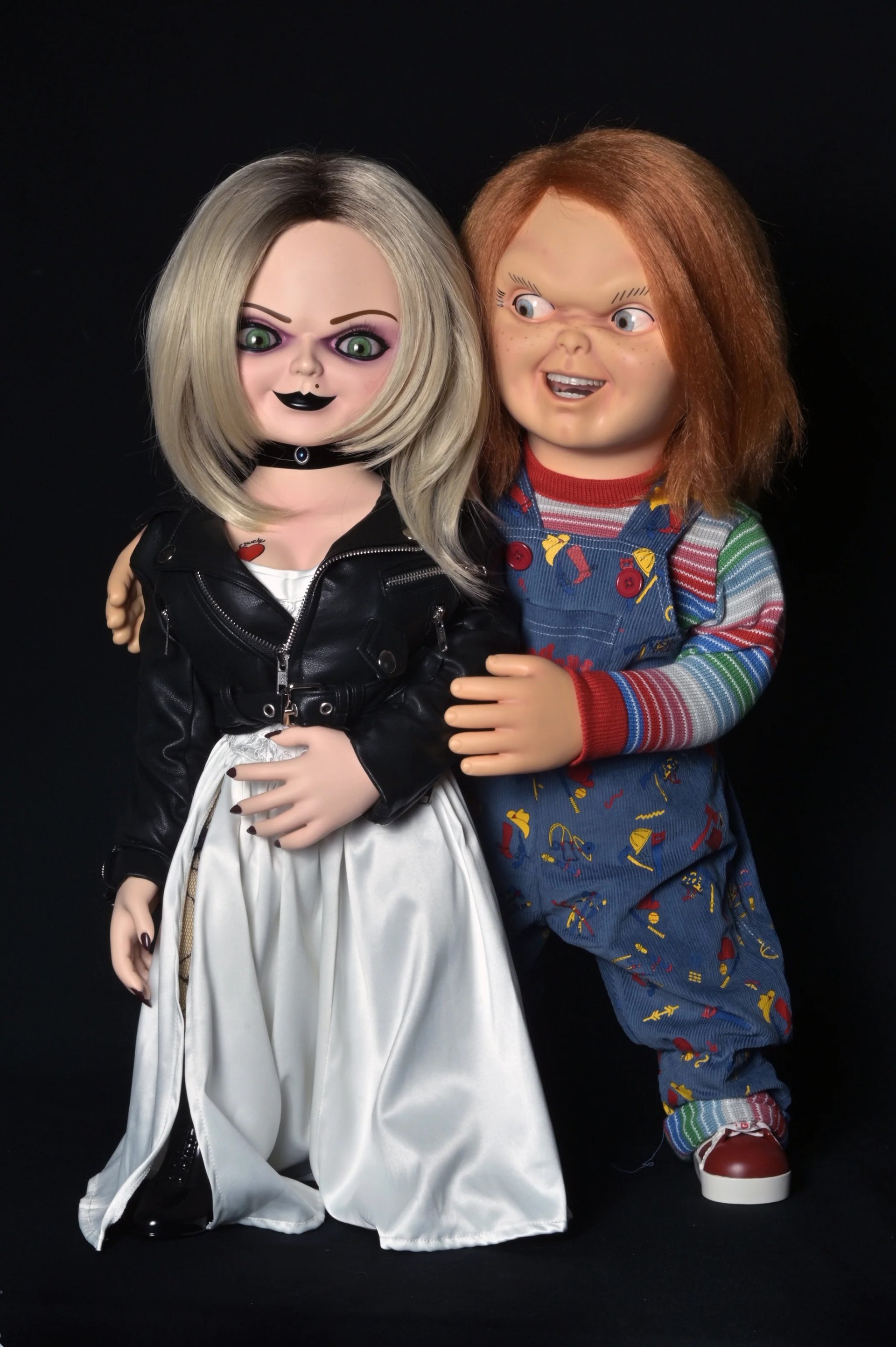 Life-size NECA Chucky and Tiffany replica dolls standing over two feet tall in their window boxes