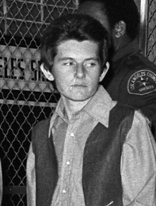 Black-and-white photo of a young woman being escorted by a Los Angeles County Sheriff's deputy outside a jail.