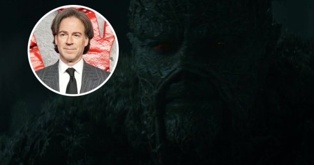 Peter Safran in a gray pinstripe suit and black tie standing in front of a red Clayface movie logo backdrop.