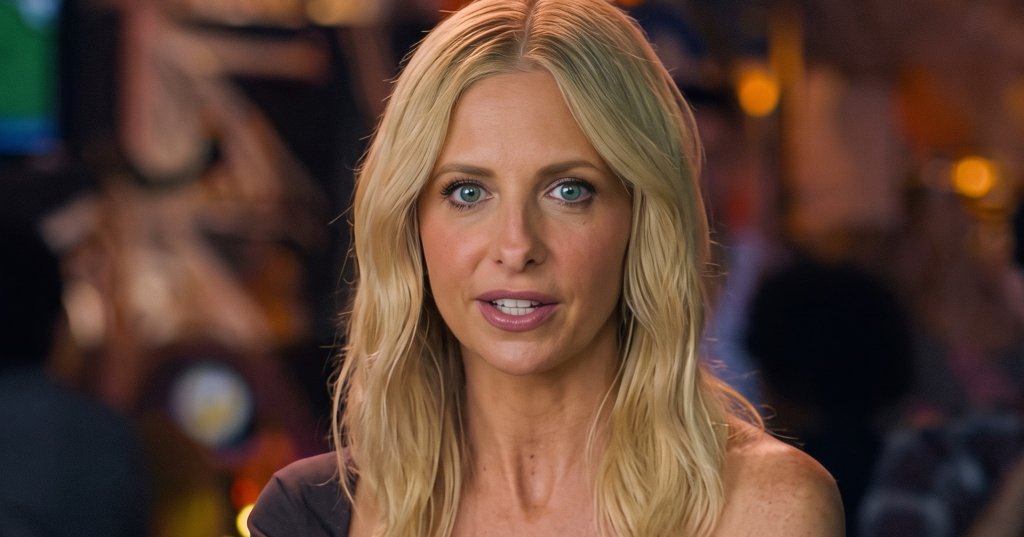 Blonde woman in an off-shoulder dark top seated at a restaurant table with glazed wings and a red cocktail with a bat trinket.