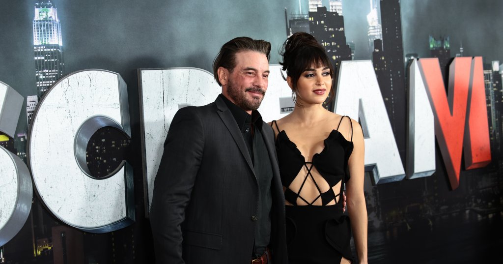 Skeet Ulrich in a dark suit and Melissa Barrera in a black cutout gown pose in front of the Scream VI premiere backdrop in New York City.